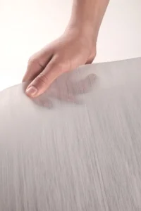 A hand holding translucent UD tape with visible continuous glass fibres